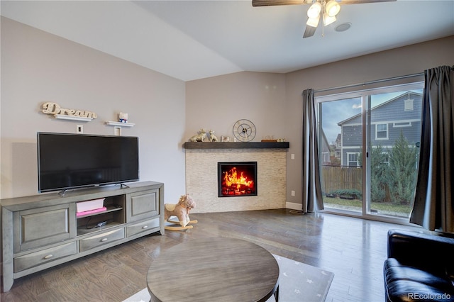 living area with lofted ceiling, ceiling fan, a lit fireplace, and wood finished floors