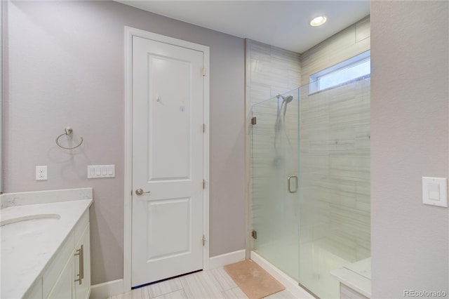 full bath featuring a stall shower, vanity, and baseboards