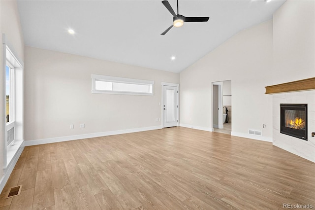 unfurnished living room featuring ceiling fan, light hardwood / wood-style flooring, high vaulted ceiling, and a fireplace