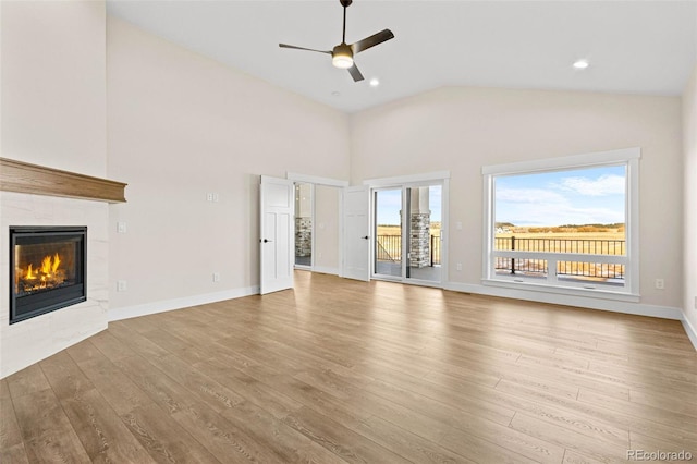 unfurnished living room with light wood-type flooring, ceiling fan, vaulted ceiling, and a fireplace