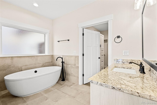 bathroom featuring a tub, tile walls, and vanity