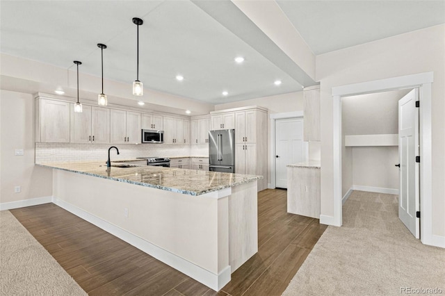 kitchen with kitchen peninsula, hanging light fixtures, appliances with stainless steel finishes, sink, and light stone counters