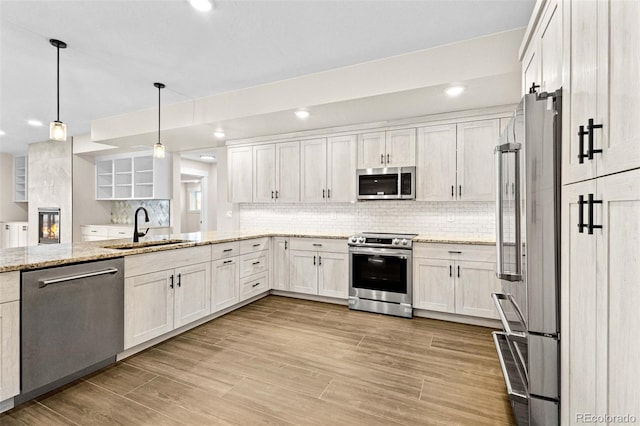 kitchen featuring light stone countertops, white cabinetry, sink, pendant lighting, and stainless steel appliances