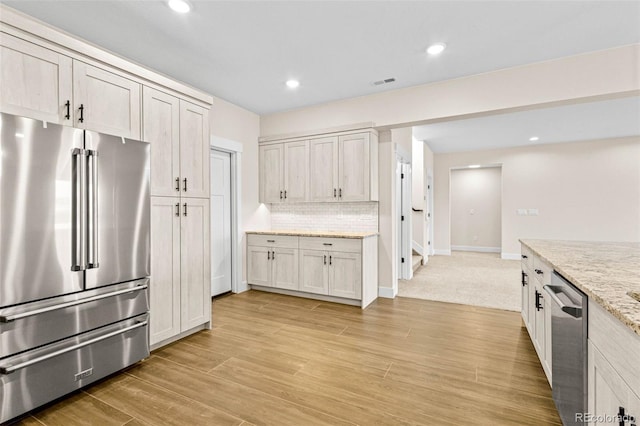 kitchen featuring backsplash, white cabinetry, light stone counters, and appliances with stainless steel finishes