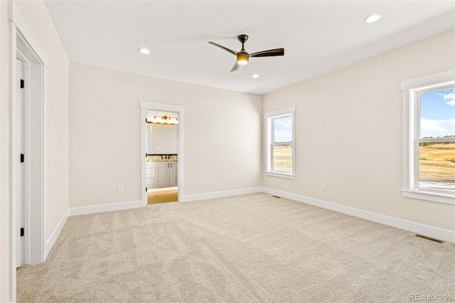 unfurnished bedroom with light colored carpet, ensuite bathroom, and ceiling fan