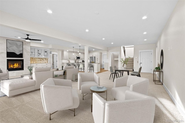 carpeted living room with a fireplace and ceiling fan