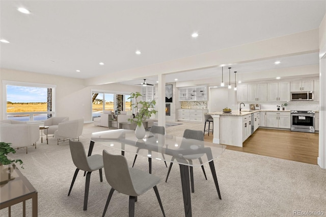 carpeted dining space featuring sink and ceiling fan