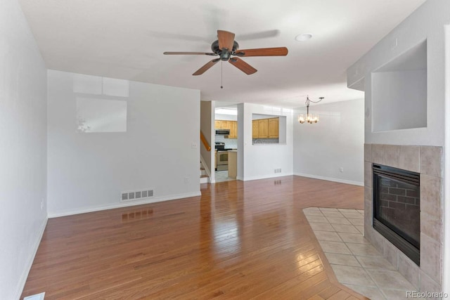 13231 Holly St Unit B, Thornton, CO 80241 - unfurnished living room with a fireplace, light wood finished floors, a ceiling fan, stairs, and a chandelier