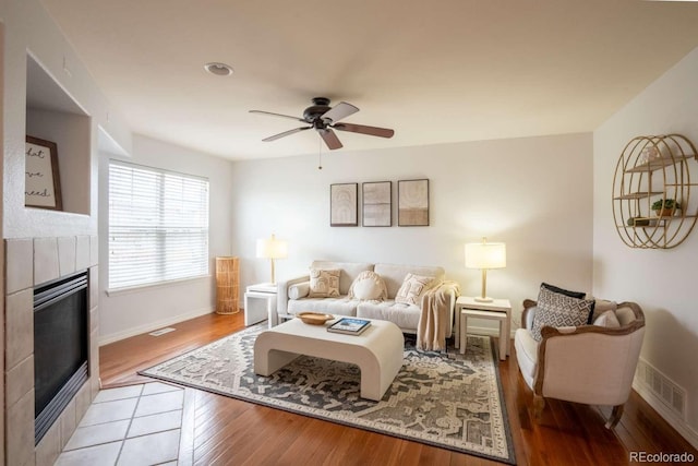 13231 Holly St Unit B, Thornton, CO 80241 - living room featuring a tile fireplace, ceiling fan, and light wood-type flooring