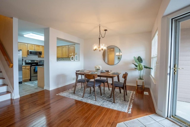 13231 Holly St Unit B, Thornton, CO 80241 - dining room featuring light wood-style floors, a chandelier, and stairs