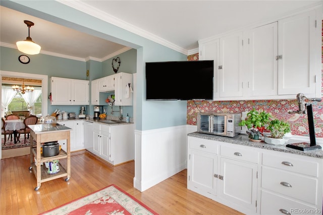 220 E Eaton Ave, Cripple Creek, CO 80813 - kitchen featuring a chandelier, light wood-type flooring, white cabinets, ornamental molding, and wainscoting