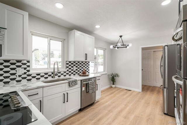 423 Nile St, Aurora, CO 80010 - kitchen featuring appliances with stainless steel finishes, a sink, decorative backsplash, a chandelier, and white cabinetry