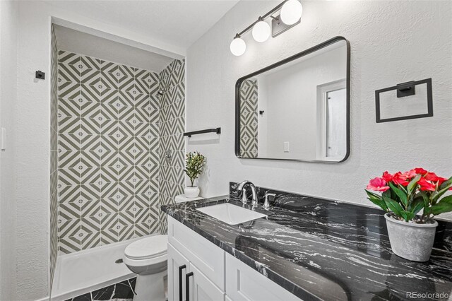 423 Nile St, Aurora, CO 80010 - bathroom featuring vanity, toilet, a shower stall, and a textured wall