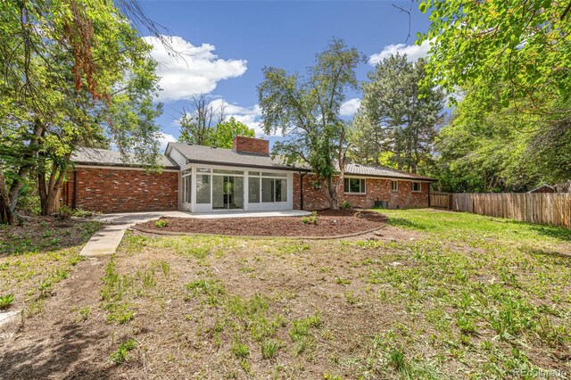 423 Nile St, Aurora, CO 80010 - back of property with brick siding, a chimney, a patio, and a sunroom