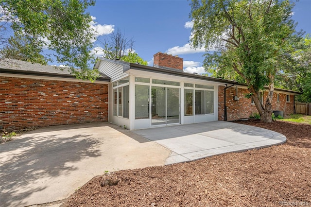 423 Nile St, Aurora, CO 80010 - rear view of house with a sunroom, a patio, a chimney, and brick siding