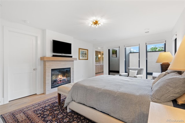 bedroom with a fireplace, ensuite bath, and light hardwood / wood-style flooring