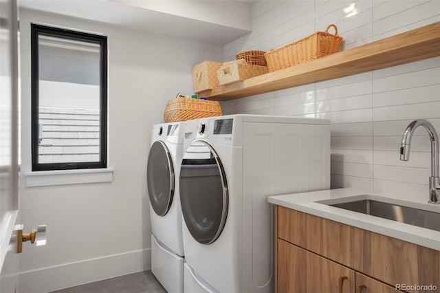 clothes washing area featuring cabinets, washing machine and dryer, and sink