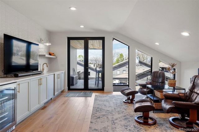 living room with lofted ceiling, sink, wine cooler, and light hardwood / wood-style flooring