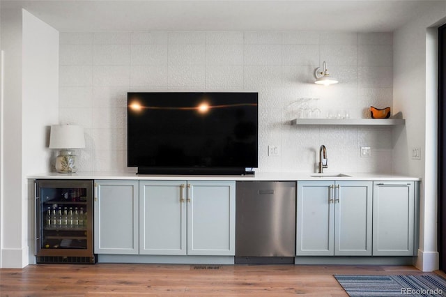 bar featuring sink, gray cabinetry, tasteful backsplash, stainless steel dishwasher, and beverage cooler