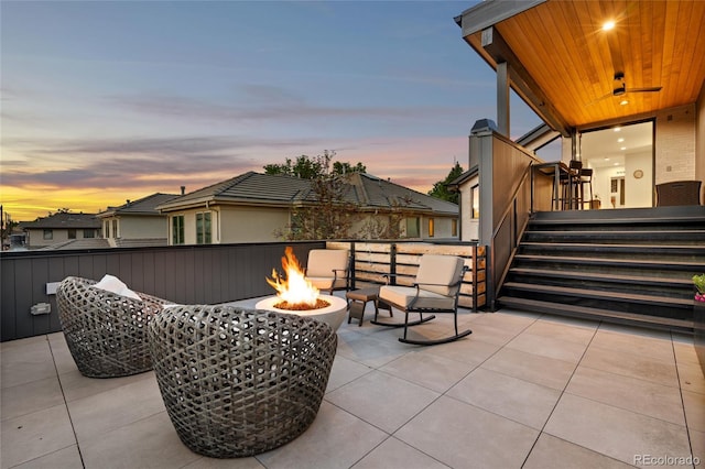 patio terrace at dusk featuring ceiling fan and an outdoor fire pit