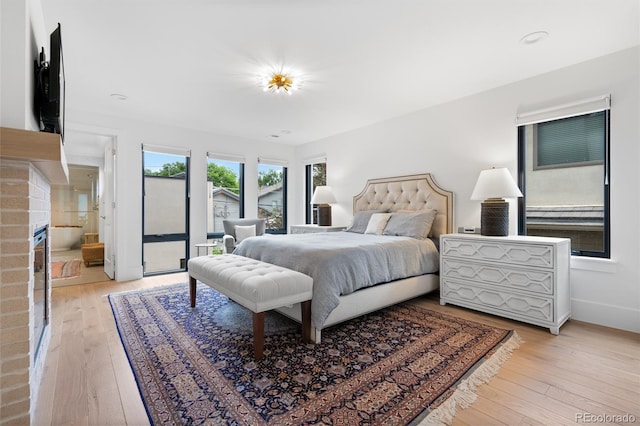 bedroom featuring a fireplace, light hardwood / wood-style floors, and access to outside