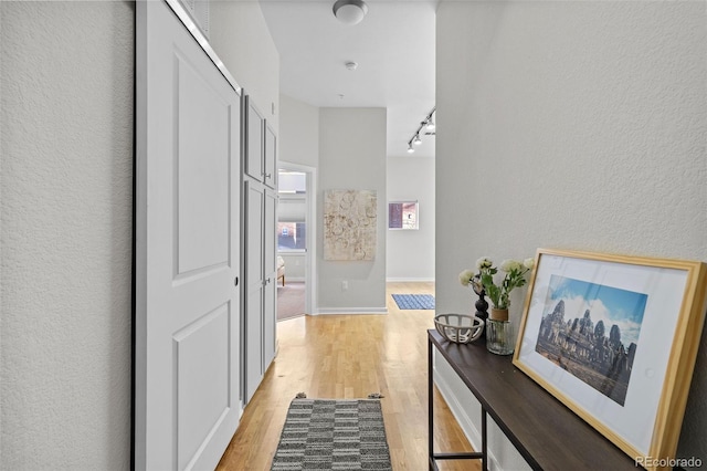 corridor featuring light hardwood / wood-style floors and track lighting