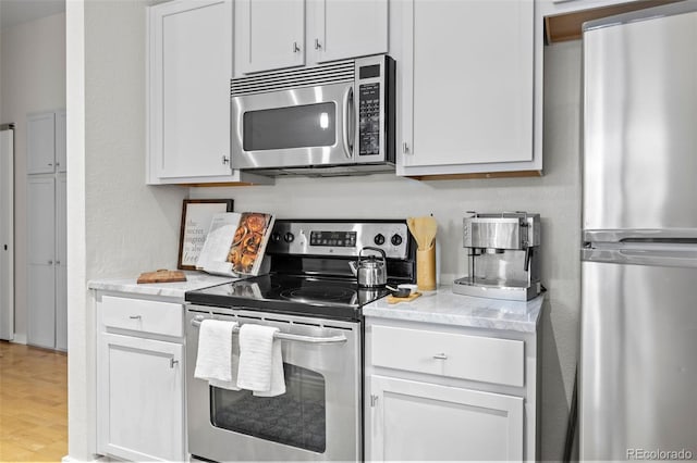 kitchen featuring white cabinets, stainless steel appliances, and light wood-type flooring