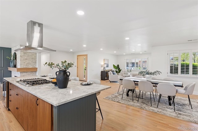 3775 S Forest Way, Denver, CO 80237 - kitchen with exhaust hood, stainless steel gas cooktop, light wood finished floors, recessed lighting, and a kitchen bar