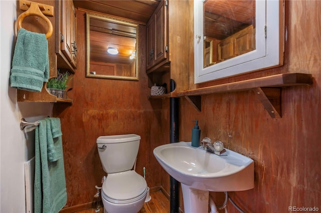 bathroom with toilet, wooden ceiling, and wood walls