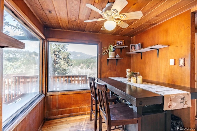 dining space featuring ceiling fan, wood walls, light wood-type flooring, and wooden ceiling