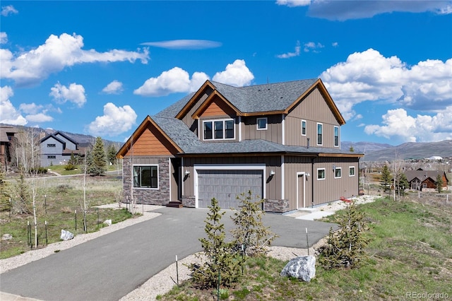 719 Saddle Ridge Cir, Granby, CO 80446 - view of front of house featuring asphalt driveway, an attached garage, stone siding, a mountain view, and roof with shingles