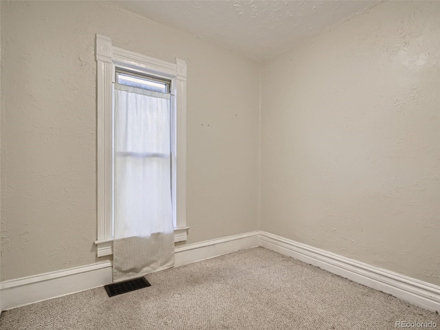 carpeted empty room with a textured ceiling