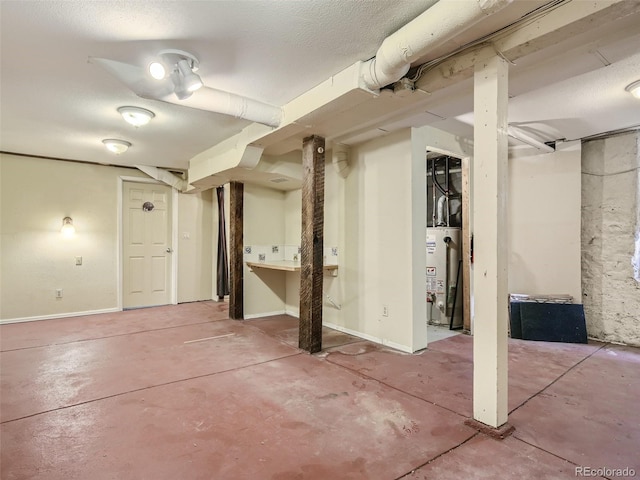 basement featuring water heater and a textured ceiling