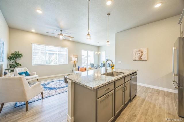 kitchen with a sink, appliances with stainless steel finishes, gray cabinets, ceiling fan, and light wood finished floors