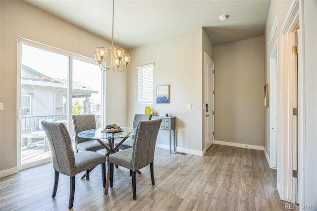 dining area featuring a chandelier, light wood-style floors, and baseboards