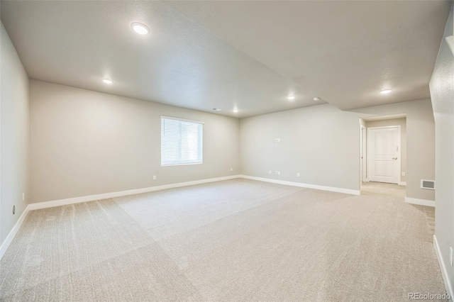 spare room featuring light carpet, recessed lighting, and baseboards