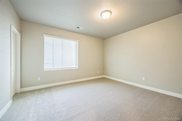 carpeted spare room with baseboards and a textured ceiling