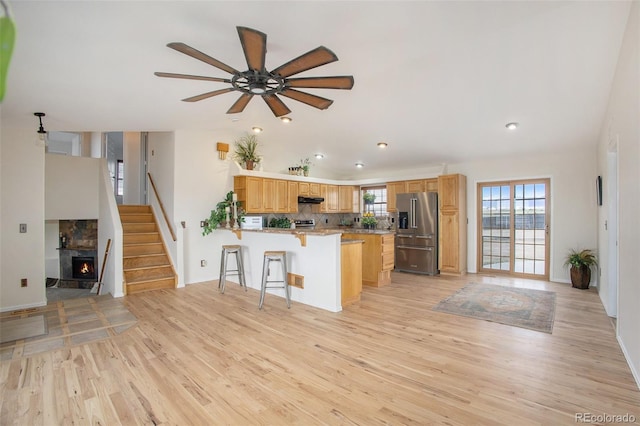 kitchen featuring light wood-style floors, high end refrigerator, a peninsula, and a wealth of natural light