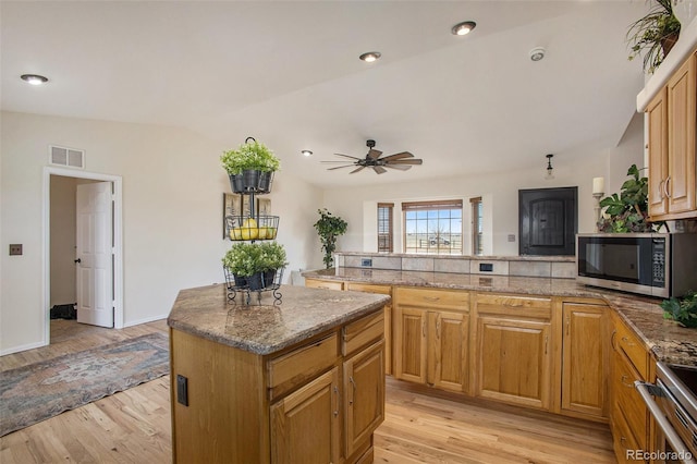 kitchen with a kitchen island, visible vents, light wood-type flooring, a peninsula, and stainless steel appliances