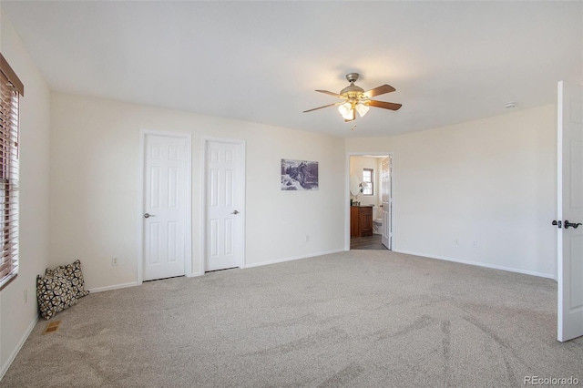 unfurnished bedroom featuring baseboards, carpet flooring, ceiling fan, and ensuite bathroom