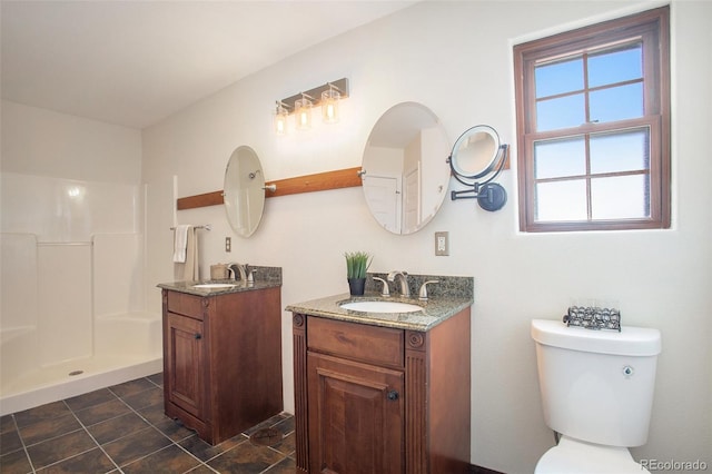 full bathroom featuring toilet, two vanities, a sink, and a shower