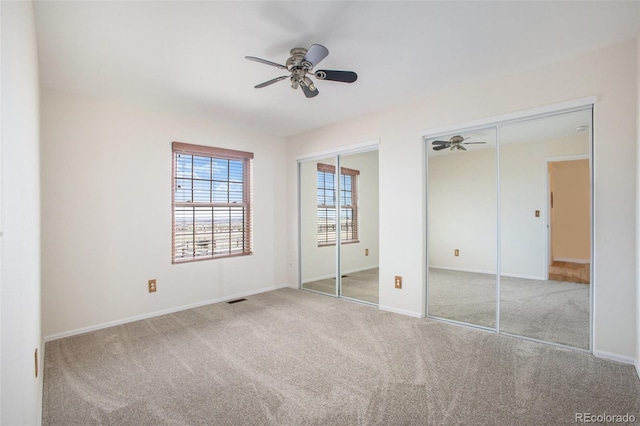 unfurnished bedroom featuring two closets, baseboards, visible vents, and carpet floors