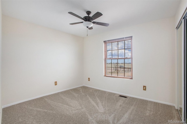 empty room with baseboards, ceiling fan, carpet flooring, and visible vents