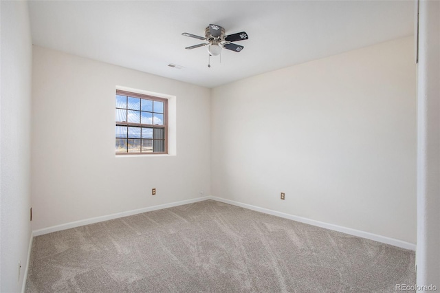 carpeted spare room featuring visible vents, baseboards, and ceiling fan