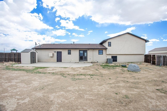 rear view of house featuring an outdoor structure, fence, a shed, stucco siding, and a patio area