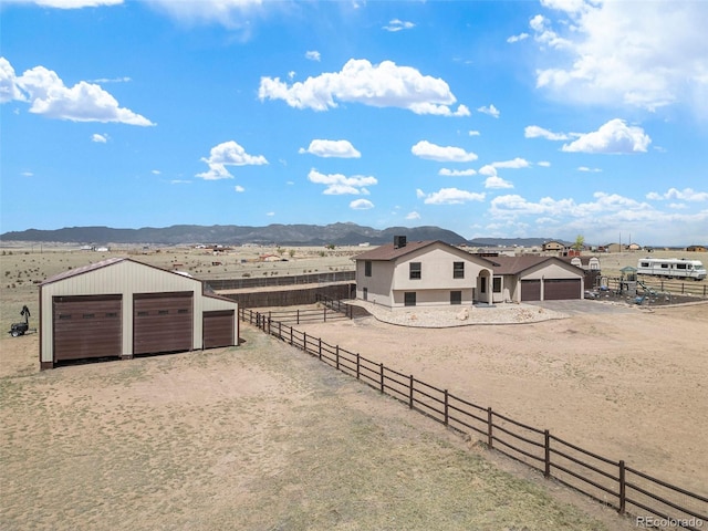 view of yard with an outdoor structure, fence, dirt driveway, a rural view, and a mountain view