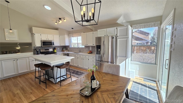 kitchen featuring lofted ceiling, appliances with stainless steel finishes, white cabinets, and a center island