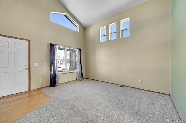 entrance foyer with high vaulted ceiling and light colored carpet