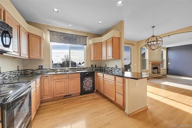 kitchen with black appliances, decorative light fixtures, tasteful backsplash, kitchen peninsula, and a chandelier