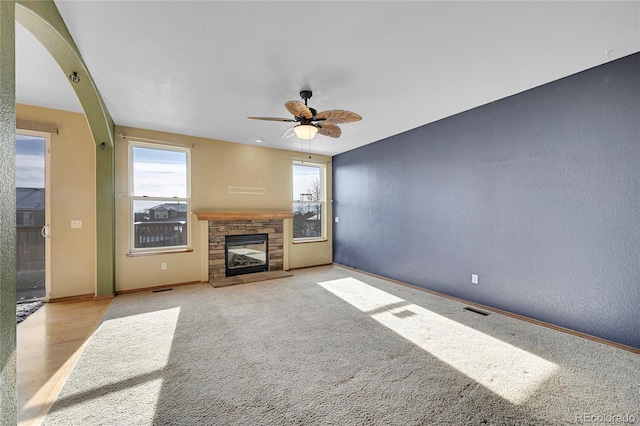 unfurnished living room with ceiling fan, light colored carpet, and a fireplace